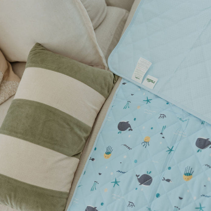 Light blue quilt with whale pattern on a beige couch
